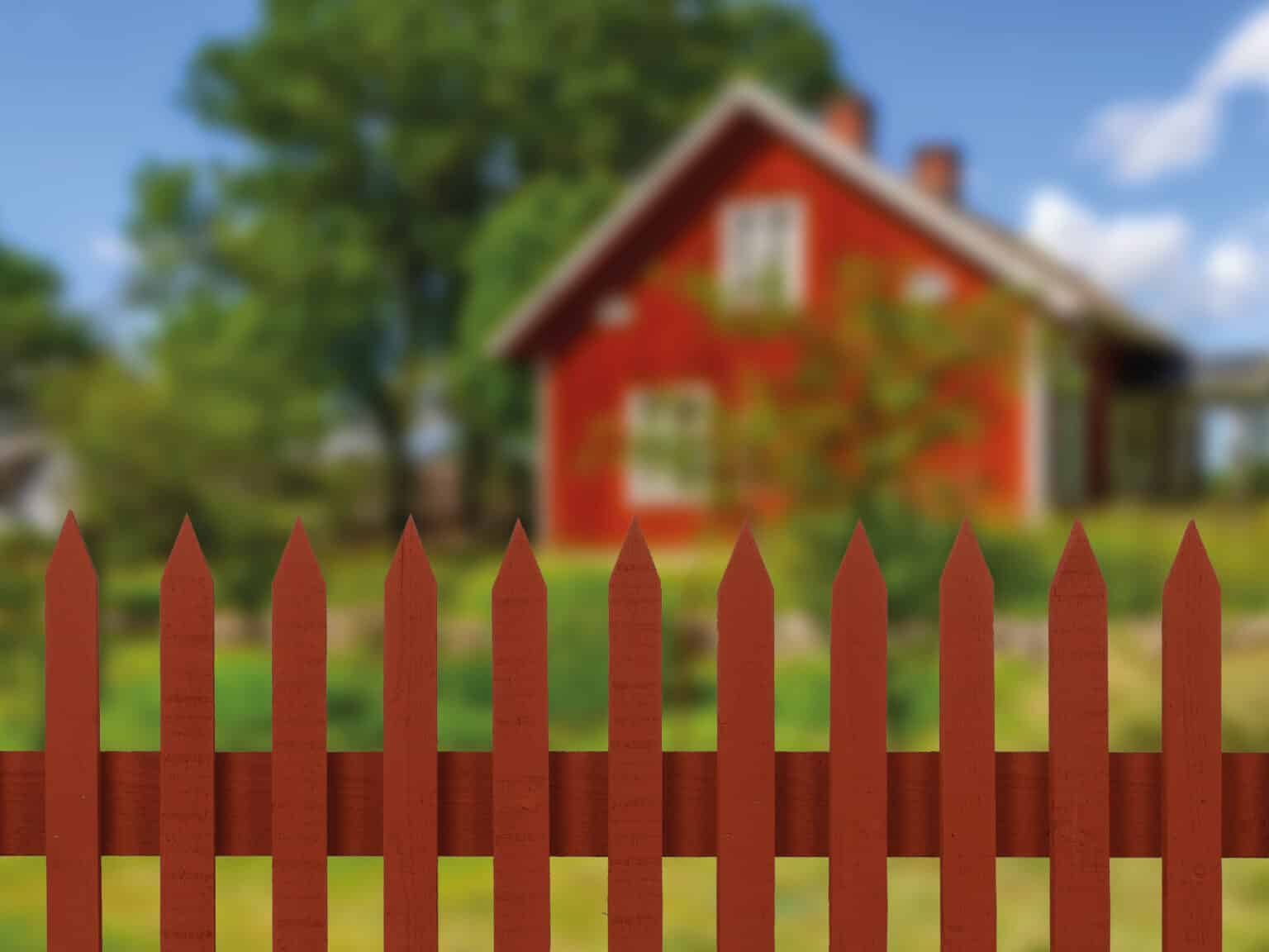 Färdig staketsektion färdigmålad med Falu Rödfärg Original framför ett hus målat med Falu Rödfärg Original.